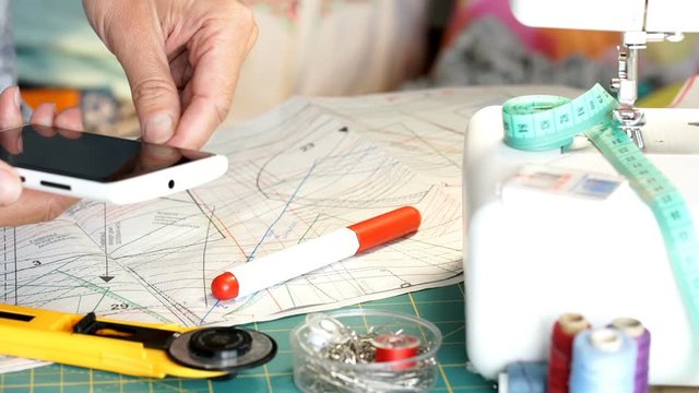 Seamstress using smartphone while doing photo of her design
