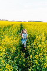 Fototapeta premium A young girl walks the yellow field