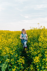 Naklejka premium A young girl walks the yellow field