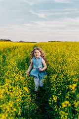 Naklejka na ściany i meble A young girl walks the yellow field
