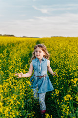 Fototapeta premium A young girl walks the yellow field
