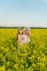 Naklejka na ściany i meble Mom and child having fun in a yellow flowering field