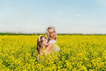 Mom and child having fun in a yellow flowering field