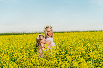 Mom and child having fun in a yellow flowering field