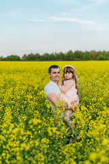 Man with child in a yellow field at sunset