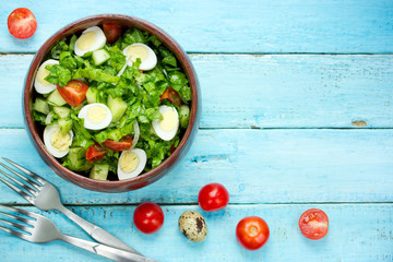 Fresh salad with green lettuce, cherry tomatoes and quail eggs