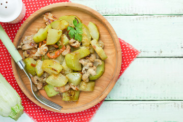 Chicken breast zucchini stir fry on wooden plate top view