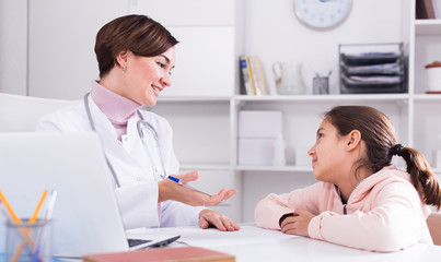 Obraz premium Doctor fills patient card for girl