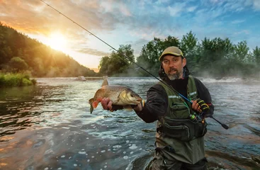 Photo sur Plexiglas Pêcher Pêcheur sportif tenant un poisson trophée. Pêche en plein air en rivière