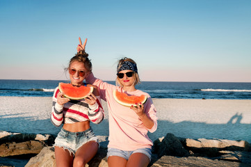 Happy girls eating watermelon on the beach. Friendship, happiness, beach, summer concept.