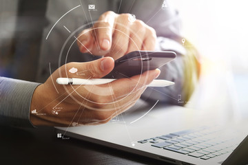 close up of businessman working with mobile phone and stylus pen and laptop computer on wooden desk...