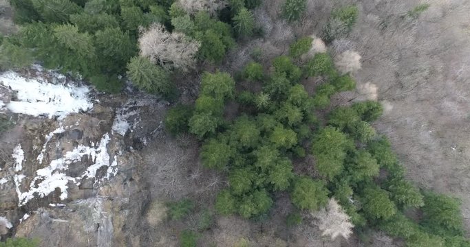 aerial drone flying over small alpine river in beautiful alpine landscape in early spring  with waterfall snow and ice melting
