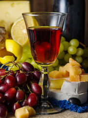 A glass of red wine with cheese and grapes on the table