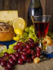 A glass of red wine with cheese and grapes on the table