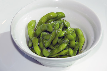 Green edamame in a white bowl