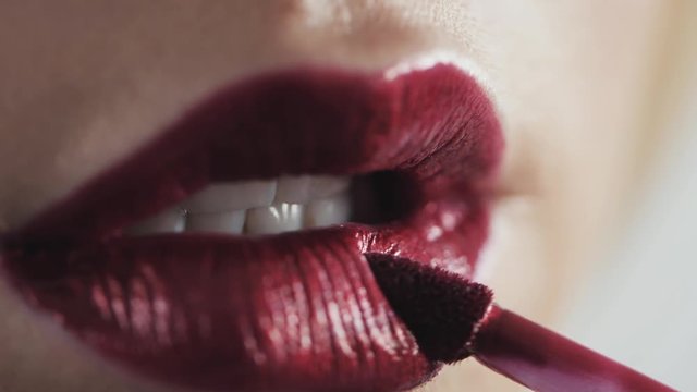 Close up shot of woman face and makeup brush applying red lipstick make-up on lips, blonde young face caucasian model