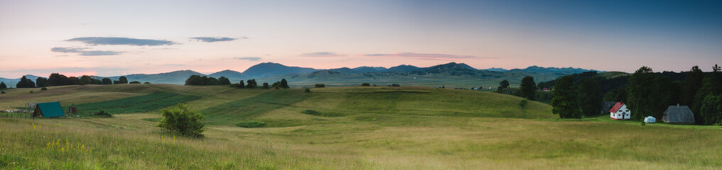 Obraz premium Panoramic view of a field and distant mountains at sunrise