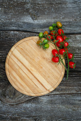 round cutting board and tomatoes on wooden surface