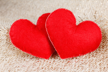 Two hearts symbol of love on burlap background.