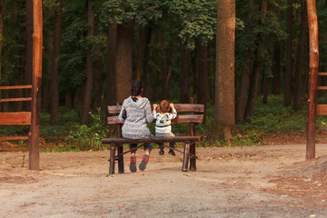 Cute little boy with his mother sitting on a bench