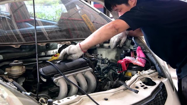 Asian mechanic man checking and maintenance engine in garage.