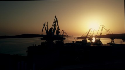 Fototapeta na wymiar Aerial view of the shipyard cranes and the sea harbour at sunset