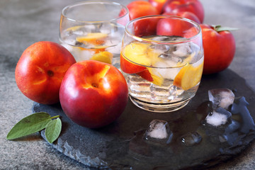 Summer diet cold drink: detox pure water with nectarine and ice cubes, two glasses
