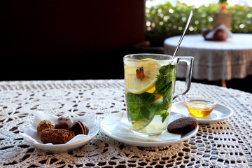 Cup of tea with lemon, mint, ginger and dessert.