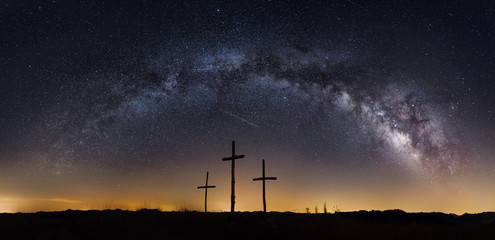 the milkyway galaxy arching over three crosses