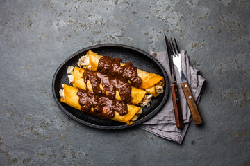 Mexican cuisine. Traditional Mexican chicken enchiladas with spicy chocolate salsa mole poblano. Enchiladas with sauce moole from Puebla, Mexico