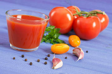 Fresh tomato juice and vegetables on blue board, healthy nutrition concept