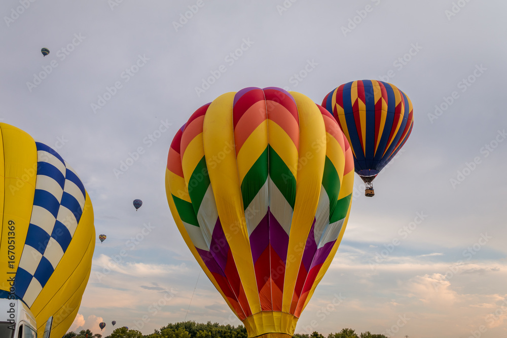 Poster Colorful array of hot air balloons float through the sky at dusk