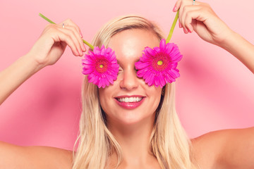 Young woman with pink garberas on a pink background