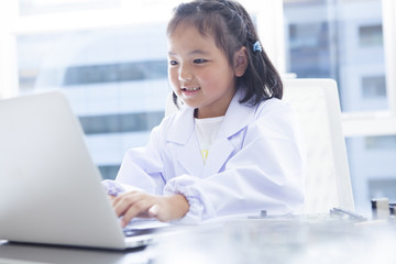 A girl wearing a white coat uses a laptop computer