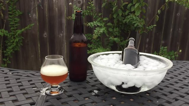 Cold beer poured into glass snifter and another beer chilling