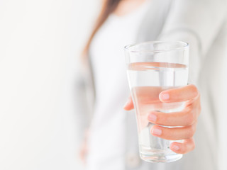 Happy beautiful young woman holding drinking water glass in her hand. Health care concept.