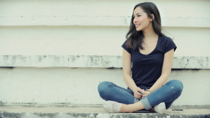 Fototapeta na wymiar Charming Asia girl smiling on face enjoying sitting outdoors