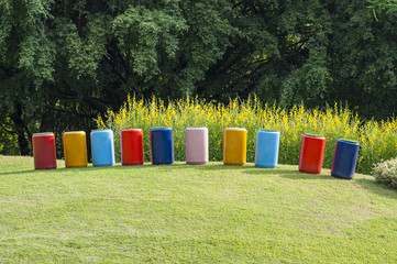 Decorate multi color concrete pipe stand on green grass.