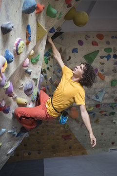Rock climber bouldering intdoors on climbing wall