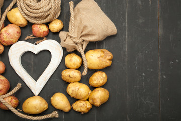 Raw potatoes on a wooden black wooden background