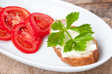 Sandwich with cheese and parsley, sliced tomatoes in  white plate