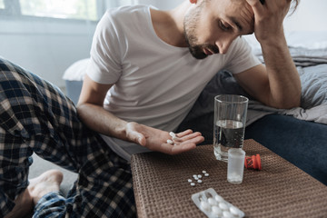 Cheerless depressed man holding a palm with three pills