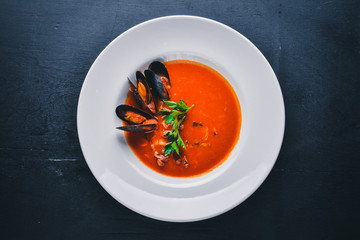 Tomato and seafood creamy soup with mussels. On a wooden background. Top view. Free space for your text.