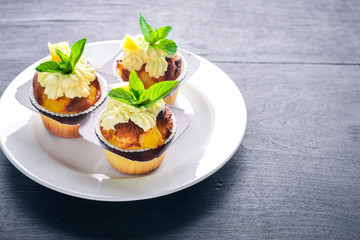 Cupcake with cream and fresh fruit. On a wooden background. Top view. Free space for your text.