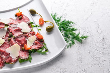 Carpaccio with meat and vegetables. Italian cuisine. On a wooden background. Top view. Free space for your text.