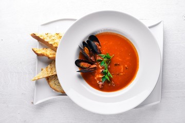 Tomato and seafood creamy soup with mussels. On a wooden background. Top view. Free space for your text.