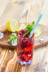 Summer drink with raspberries, lime and ice on a old wooden table