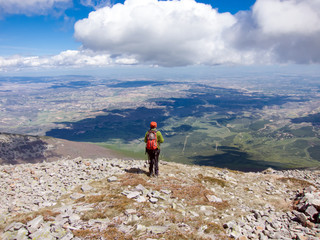 Woman hiker with backpack watching the spectacular landscape from the summit of Moncayo mountain, Aragón, Spain