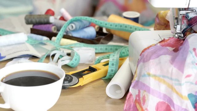 View of coffee and sewing machine with equipment lying on the table, steadycam shot
