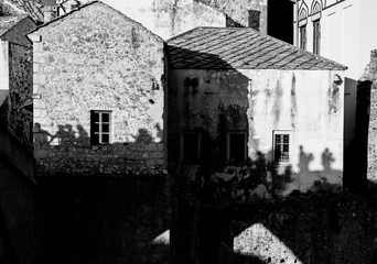 people silhouette on medieval stone house wall, Mostar, Bosnia and Herzegovina, black and white, concept